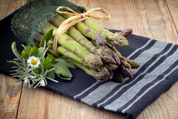 Bunch of fresh asparagus on wooden table. Green asparagus and herbs.