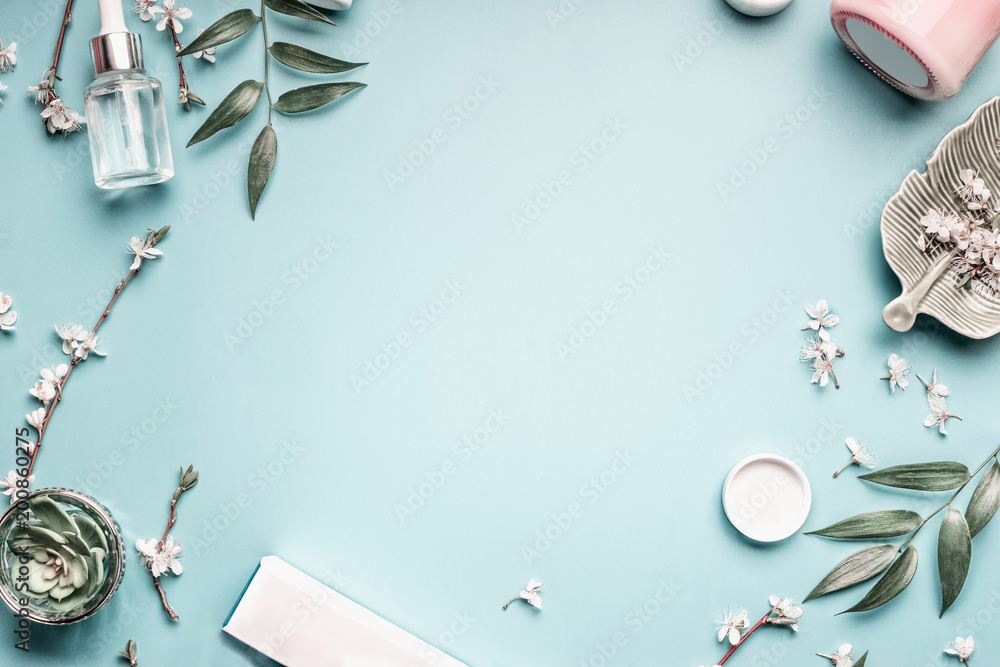 Facial cosmetic products, leaves and cherry blossom on blue table - obrazy, fototapety, plakaty 
