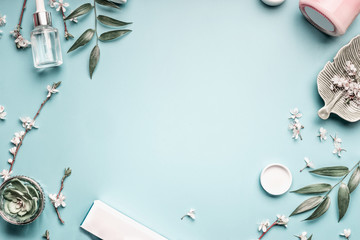 facial cosmetic products, leaves and cherry blossom on blue table