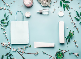 Wall Mural - beauty concept with facial cosmetic products, shopping bag and cherry blossom on pastel blue desktop