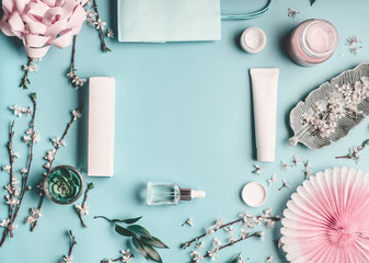 Wall Mural - Beauty concept with facial cosmetic products, shopping bag and twigs with cherry blossom on pastel blue desktop background. Modern spring skin care trends, top view, frame, flat lay. Branding mock up