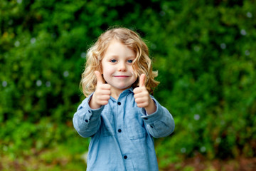 Wall Mural - Happy small child with long blond hair and saying OK