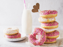 Stack Of Pink And White Donats With Bottle Of Milk Over White Background