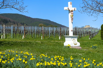 jesus cross in front of daffodils spring flowers and hambach castle in Sankt Martin, Palatinate, Germany