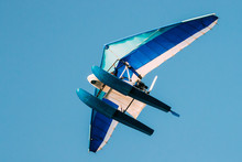 Motorized Hang Glider Flying On Blue Clear Sunny Sky Background
