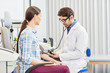 © pressmaster - Male doctor measuring blood pressure to young woman