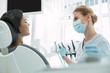 Good mood. Cheerful blond dentist wearing a mask and looking at her patient