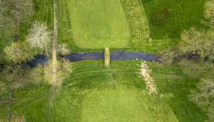 Poster - Drone view of a golf course with a small river and a bridge