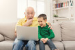 © Prostock-studio - Little boy teaching his grandfather to use laptop