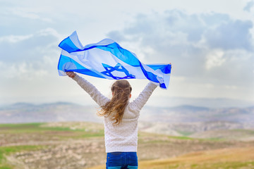 Little patriot jewish girl standing  and enjoying with the flag of Israel on blue sky background.Memorial day-Yom Hazikaron, Patriotic holiday Independence day Israel - Yom Ha'atzmaut concept