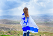 Little Patriot Jewish Girl Standing  And Enjoying With The Flag Of Israel On Blue Sky Background.Memorial Day-Yom Hazikaron, Patriotic Holiday Independence Day Israel - Yom Ha'atzmaut Concept