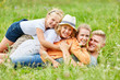 © Robert Kneschke - Familie und Kinder kuscheln zusammen im Gras