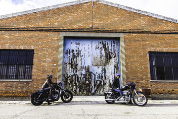 Modern bikers sits on classic motorcycle looking at the sun. Outdoor portrait and urban lifestyle