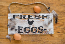 Wooden Sign That Says Fresh Eggs With Feathers And Brown Eggs