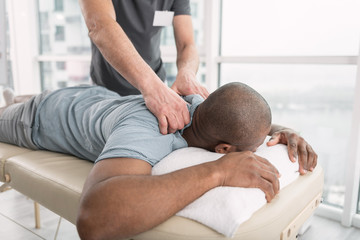 Wall Mural - Professional therapy. Nice pleasant man lying on the medical couch while having a professional massage