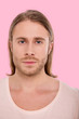 © Viacheslav Yakobchuk - Ruining stereotype. The portrait of a blue-eyed bristled man with a long hair posing for the camera against a pink background while wearing a beige t-shirt