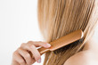 Young woman with comb brushing her wet, blonde, perfect hair after shower on the white background. Care about beautiful, healthy and clean hair. Beauty salon concept. Side view.