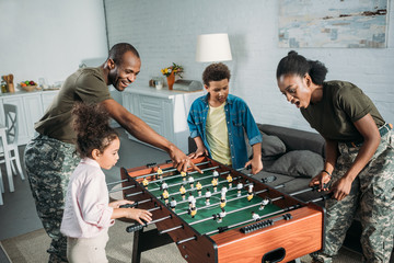 Wall Mural - Woman and man in army uniform and cheerful kids playing table football