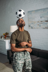 Wall Mural - African american soldier playing with football ball on head