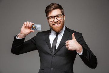 Poster - Portrait of a happy young businessman holding credit card