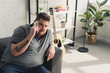 © LIGHTFIELD STUDIOS - overweight man talking by smartphone on sofa at home