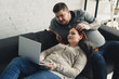 © LIGHTFIELD STUDIOS - boyfriend touching girlfriend hair and looking at laptop at home