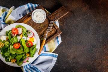 Fresh spring vegetable salad, dark concrete background above copy space