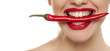 Young sexy woman holding a chili with her teeth on white background