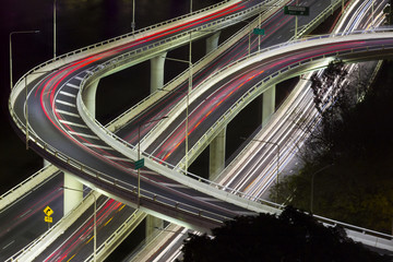 Aerial view of modern urban traffic road at night. Cityscape overpass with light trails. Brisbane Riverside Expressway, Australia.