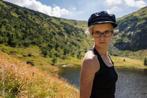 Fotografia Young serious woman in black hat and glasses looks away