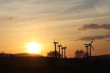 Wind power station in sunset. Romantic evening and modern technologies of ecologically clean electricity. Protection of the environment. Bright Future. An alternative way of extracting energy.