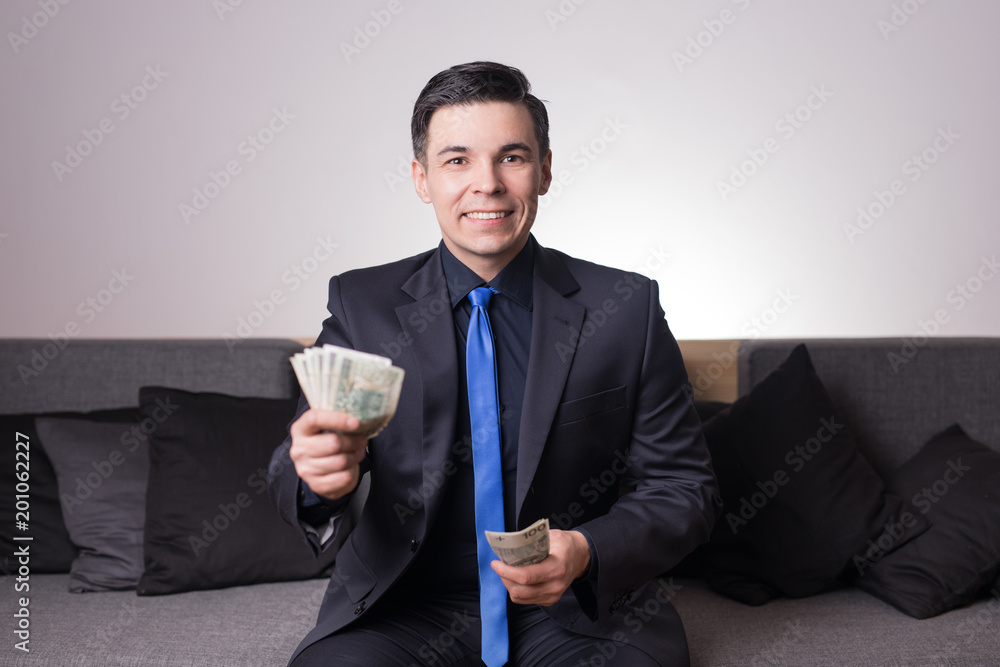 Młody mężczyzna liczy pieniądze - finanse nieruchomości inwestycje - obrazy, fototapety, plakaty 