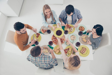 High angle view of stylish friendly attractive positive best friends at the table enjoying delicious dishes enjoying meeting in modern dinning room celebrating holiday sharing plate with salad