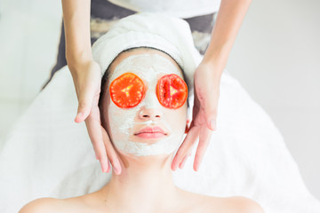 Red Tomato slice on eyes, relax spa background, health and beauty concept, beauty woman is relaxing facial by handy massage.