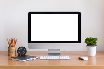 All in one computer, mouse, keyboard, clock, pencils, note book and tree vase  on wooden table