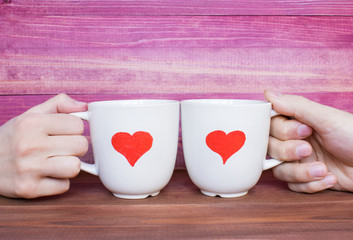 Two white mugs with drawn hearts on the pink background, love concept.