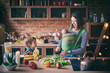 © sandsun - Happy young family, beautiful mother with two children, adorable preschool boy and baby in sling cooking together in a sunny kitchen.