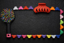 A Frame Of Multi-colored Colorful Rubber Bands For Hair, Combs And Hair Clips On A Black Background.Copy Space.