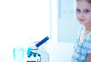 Schoolgirl looking through microscope in science class.