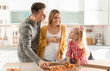 © New Africa - Pregnant woman and her family eating pizza in kitchen