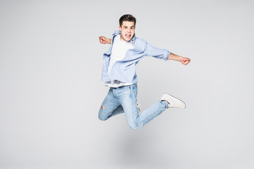 Full-length photo of funny man in casual t-shirt and jeans running or jumping in air isolated over white background