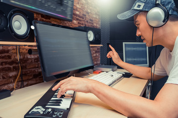Wall Mural - asian musical producer arranging a song on digital recording equipment in home studio