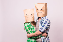 Love, Family And Relationship Problems Concept - Unhappy Couple Covering Their Sad Faces With Paper Bag Over White Background.