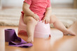 Closeup of legs of one year old baby toddler girl child sitting on potty in nursery room