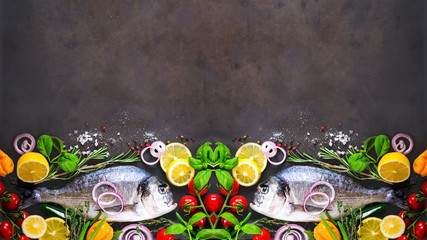 Wall Mural - Fresh uncooked fish, dorado, sea bream with lemon, herbs, vegetables and spices on stone background. Top view. Banner