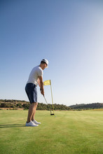 A Man Hitting Golf Ball At Hole With Flag