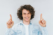 © iuricazac - Portrait of curly hair amazed handsome man has happy expression, indicate index fingers up, good idea for advertisement. Smiling cheerful male isolated on white studio wall. Copy space. People race