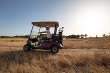 Side View Of Man Riding Golf Cart