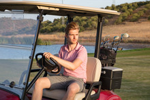 Young Handsome Golfer Driving Golf Cart With Bag Of Clubs