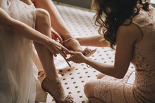 A Girlfriend Helps A Bride To Put On Her Wedding Shoes. Beautiful Female Legs Closeup